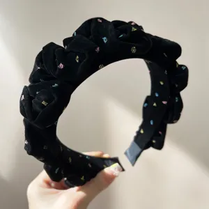 Detailed texture of black flocked pleated headband with colorful glitter stars