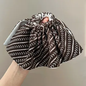 Detailed close-up of brown sequined headband with elegant herringbone pattern embroidery