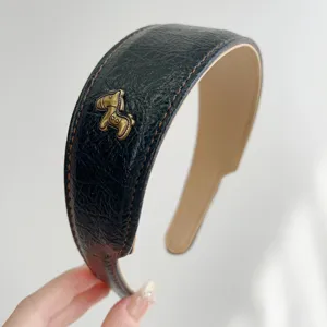 Nahaufnahme eines schwarzen Vintage-Lederstirnbands mit goldener Pferdefigur-Verzierung