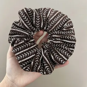 Detailed macro shot of a brown sequined scrunchie with white v-shaped embroidery patterns