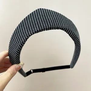 Vue détaillée d'un serre-tête en tweed à pointe avec sangle élastique noire réglable.