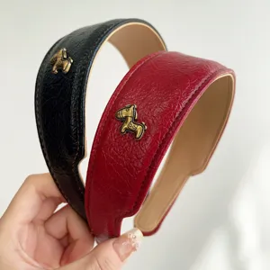 Detaillierte Nahaufnahme von breiten Vintage-Haarreifen aus Kunstleder mit goldenen Pferden