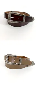 Gros plan détail de ceinture en cuir vintage western avec boucle et bout en métal gravé.