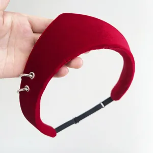 Close-up of a red velvet padded headband featuring decorative silver rings and soft texture.
