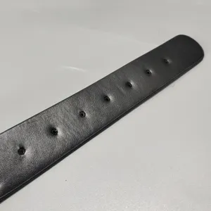 Vue détaillée d'une sangle de ceinture en cuir noir, classique pour jeans et robes.