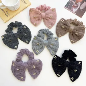 Detail van gebreide strik-scrunchies met gouden kruissterren in verschillende kleuren