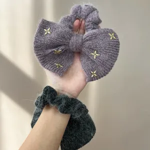 Detailopname van een paarse gebreide strik scrunchie met gouden sterrenhangers