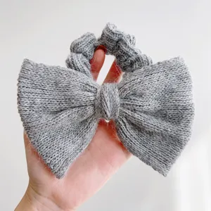 Detailopname van een grijze gebreide strik scrunchie van zacht nertsgaren met fijne textuur