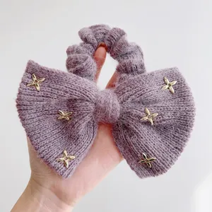 Detail van een zachte paarse nertswol strik scrunchie met gouden ster bedeltjes voor haar