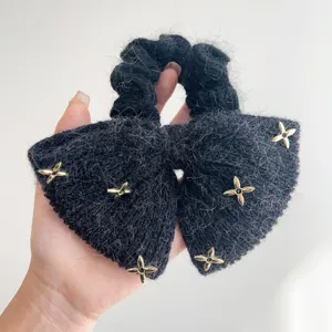 Detailweergave van zwarte nertswollen strik-haarscrunchie met gouden sterversieringen