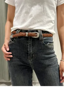 Slim brown suede leather belt styled with high-waisted jeans, perfect detail shot view.