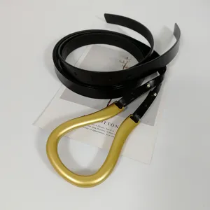 Detailed view of women's black leather belt featuring a large gold U-shaped buckle.