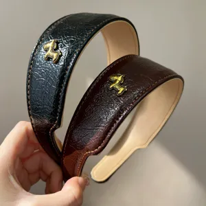 Nahaufnahme von Vintage-Lederstirnbändern in Schwarz und Braun mit goldenem Pferd