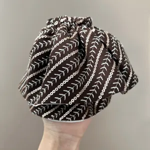 Close-up of brown headband with white striped embroidery and silver sequins