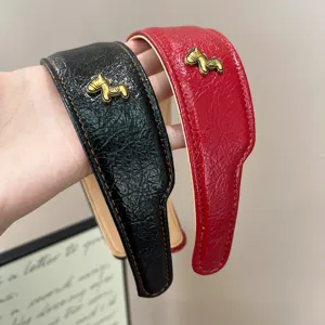 Detail von Vintage-Leder-Haarreifen in Schwarz und Rot mit goldener Pferdefigur.