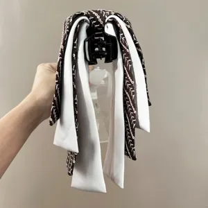 Detailed view of an elegant hair claw clip featuring brown striped and white ribbons.