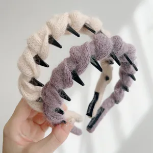 Detail van gevlochten wollen haarbanden met antislip tanden in crème en paars