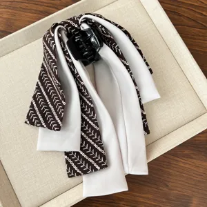 Elegant hair claw clip with detailed brown leaf pattern ribbon and white fabric layers.