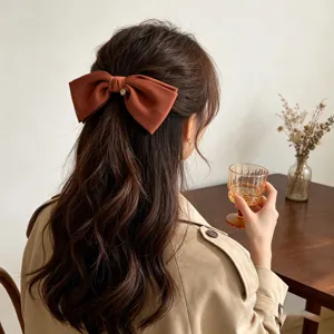 Elegant large terracotta satin bow hair clip with gold heart charm on model back