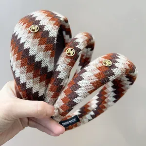 Close-up van gebreide retro Fair Isle-hoofdbanden met een gouden M-logo detail.