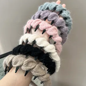 Gedetailleerde close-up van gevlochten wollen haarbanden met antislip tanden in winterkleuren