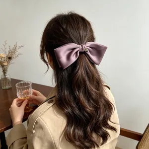 Elegant purple satin bow hair clip shown on a half-up hairstyle from the back view