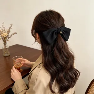 Rear view of an elegant black oversized bow hair clip worn on long wavy brown hair