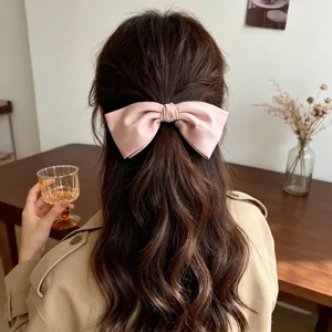 Elegant pink bow hair clip with heart charm shown on model hair for half-up hairstyle.