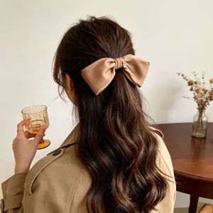 Detailed back view of an elegant tan satin bow hair clip holding a half-up hair style