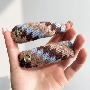 Detailopname van Fair Isle gebreide haarspelden in vintage stijl met gouden M-logo