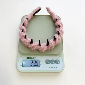 Detailopname van het gewicht van 29,5 g van deze roze gevlochten wollen haarband