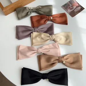 Detailed close-up showing a variety of elegant satin bow hair clips with metal spring clips.