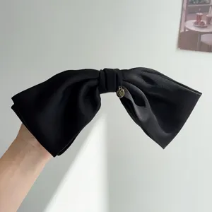 Elegant large black satin 3D bow hair clip featuring a delicate gold heart charm