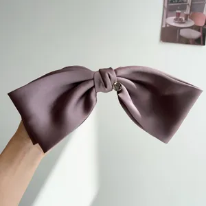 Detailed view of an elegant purple satin 3D bow hair clip with a heart charm