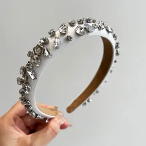 Detailaufnahme eines weißen gepolsterten Stirnbands mit funkelndem klarem Strassbesatz.