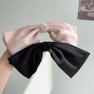 Elegant oversized satin bow hair clips in pink and black with golden heart charms.