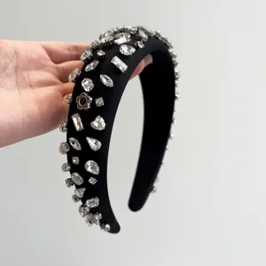 Detailaufnahme eines schwarzen gepolsterten Stirnbands mit funkelnden Kristallsteinen.