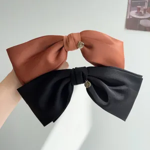Close-up detail of elegant 3D satin bow hair clips with a gold heart charm accent.
