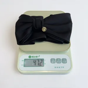 Black 3D bow hair clip detail on scale showing weight of 47.2g for back-of-head styling.