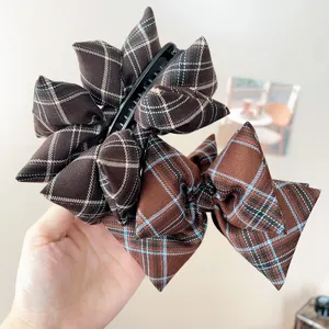 Detail of retro brown plaid fabric claw clip with elegant pleated bow design.