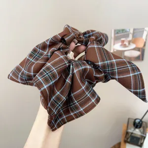 Close-up of a brown retro plaid pleated hair scrunchie featuring bow-like design