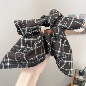 Detailed shot of a vintage coffee brown plaid scrunchie with a large bow hair tie