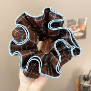 Detailed close-up of a retro brown plaid fabric scrunchie with light blue wavy piping