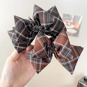 Detailed view showing textures of vintage plaid bow hair accessories in brown colors.