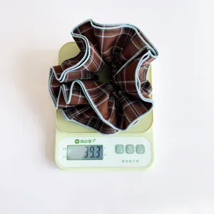 Brown plaid fabric scrunchie weight demonstration on a digital scale showing 39.3g