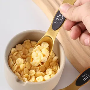 Gold stainless steel measuring spoon set with clear volume markings for easy kitchen use.