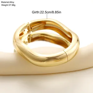 Vista detallada del brazalete de onda dorado con contorno 22,5cm en aleación pulida.