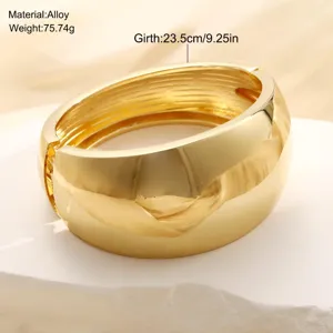 Detalle de un brazalete ancho de aleación dorada pulida con acabado de espejo.