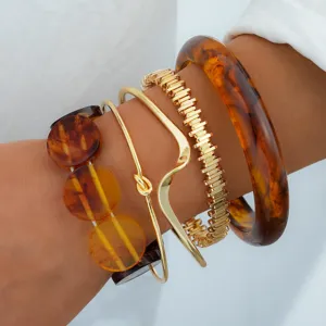 Dettaglio ravvicinato di una serie di bracciali in metallo dorato e resina ambrata
