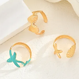 Detailansicht von drei goldfarbenen, verstellbaren Ringen mit Seestern- und Muschelmotiven
